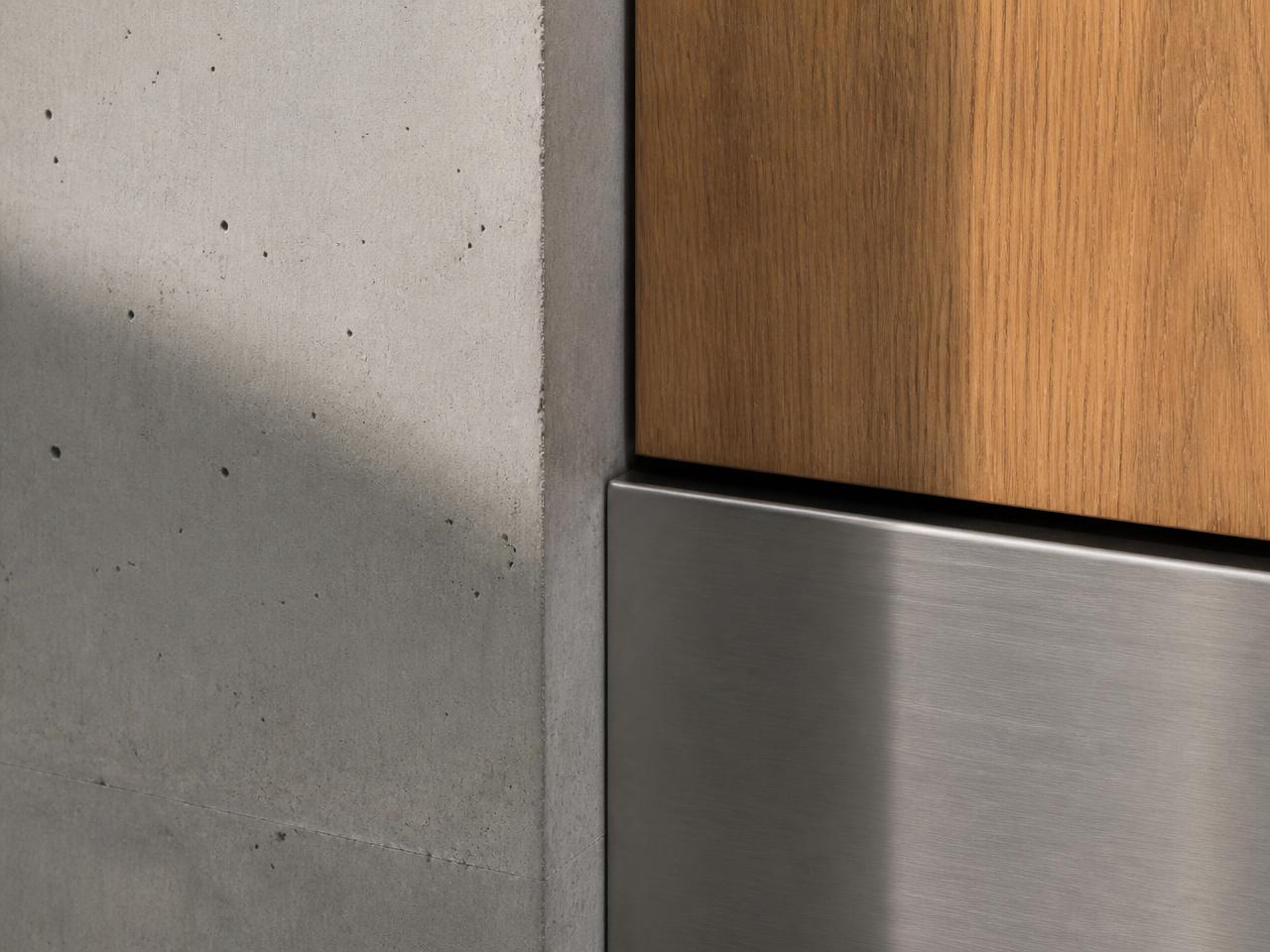 Detail: Sichtbeton trifft auf Eichenholz und gebürsteten Stahl